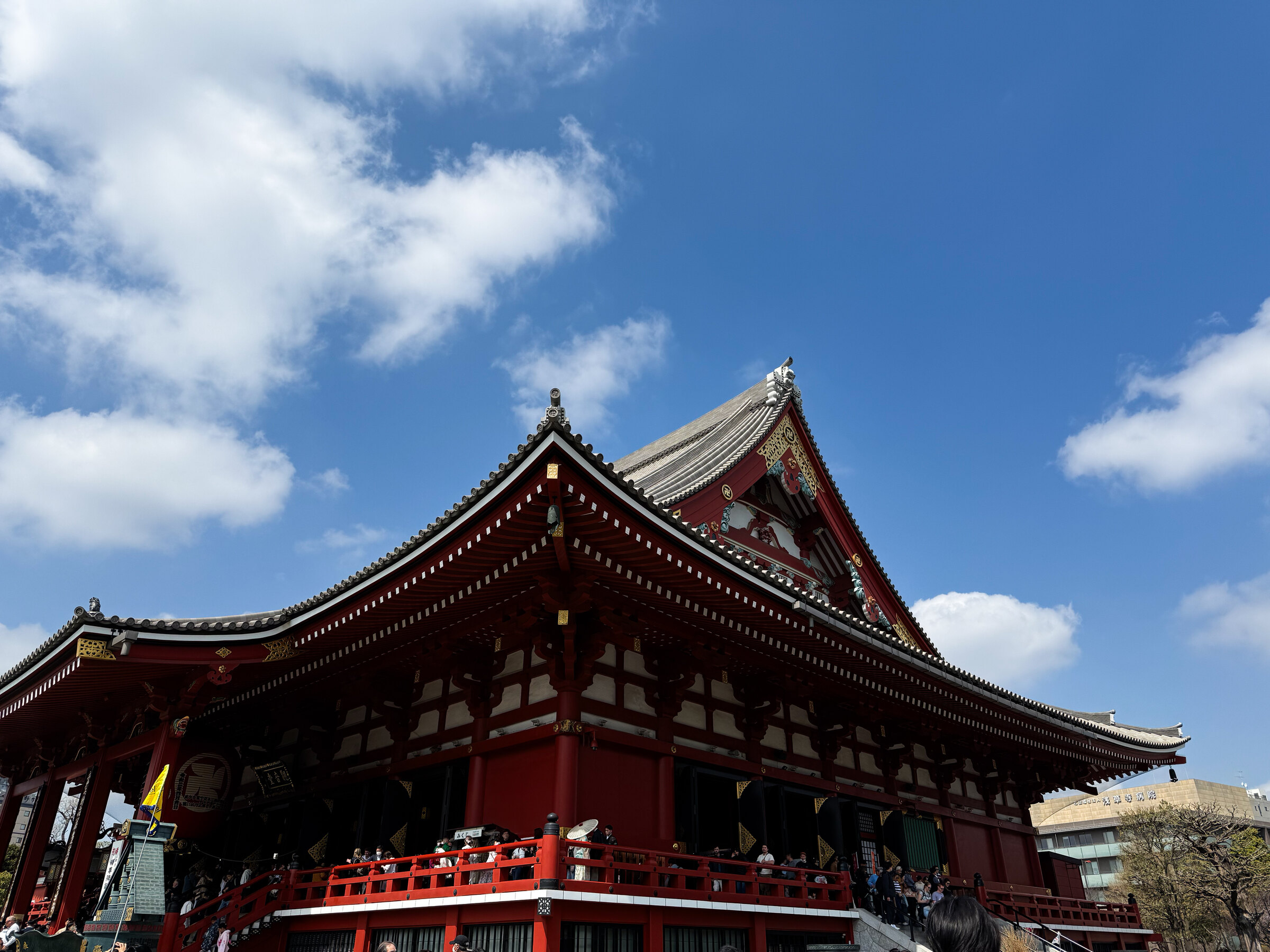 A red temple roof at Senso-ji against a bright blue sky.