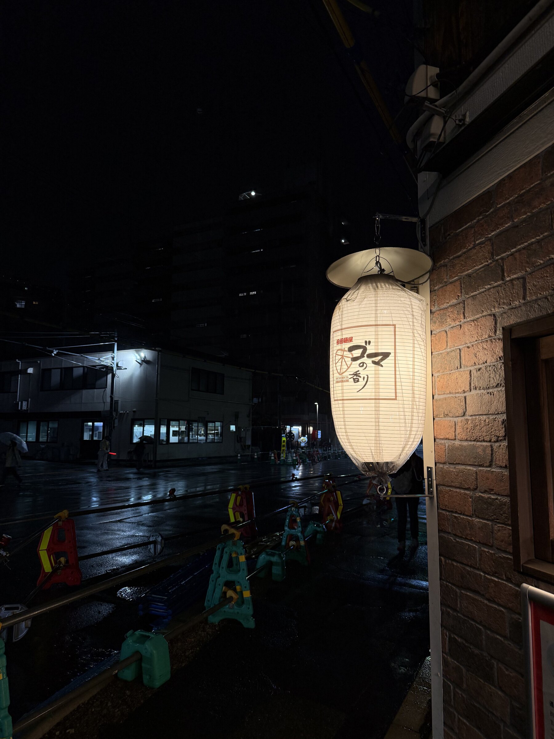 A glowing lantern on a rainy street at night.