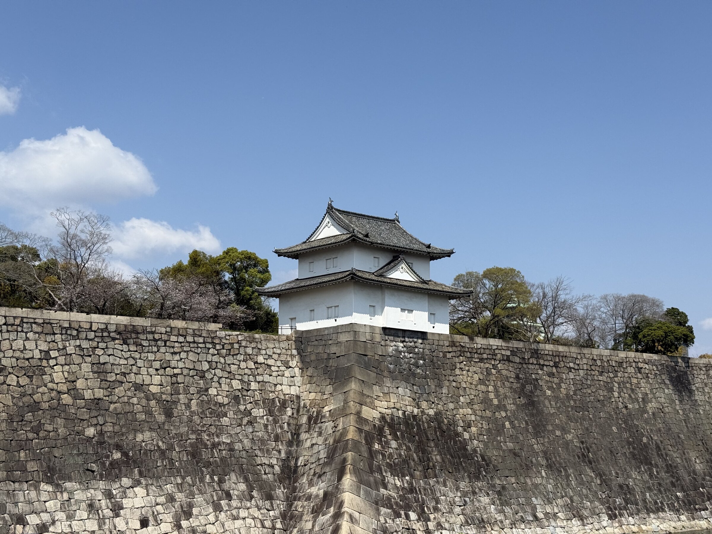 Osaka Castle rising above a stone wall under a clear sky.