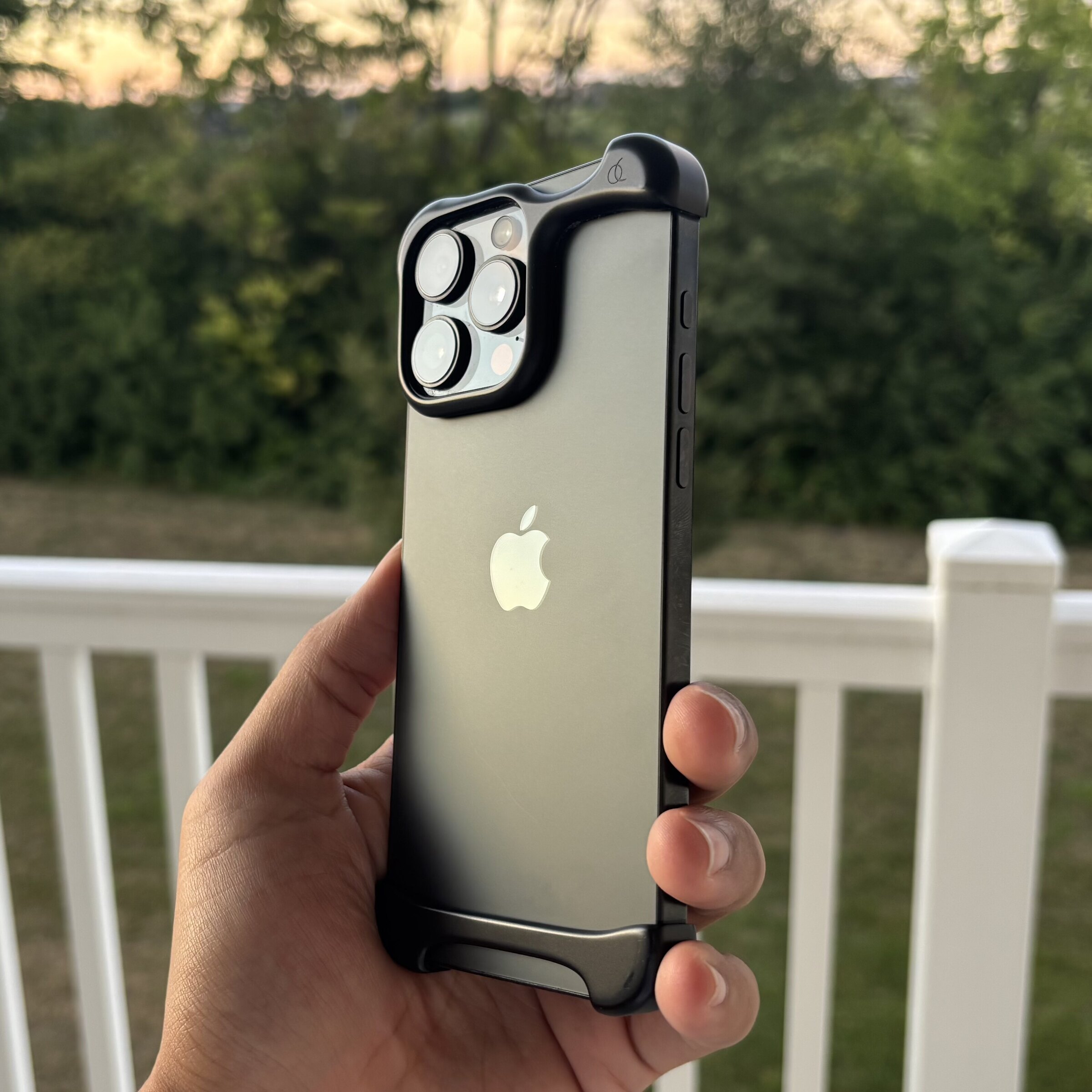An iPhone 16 Pro Max held up outdoors at golden hour.