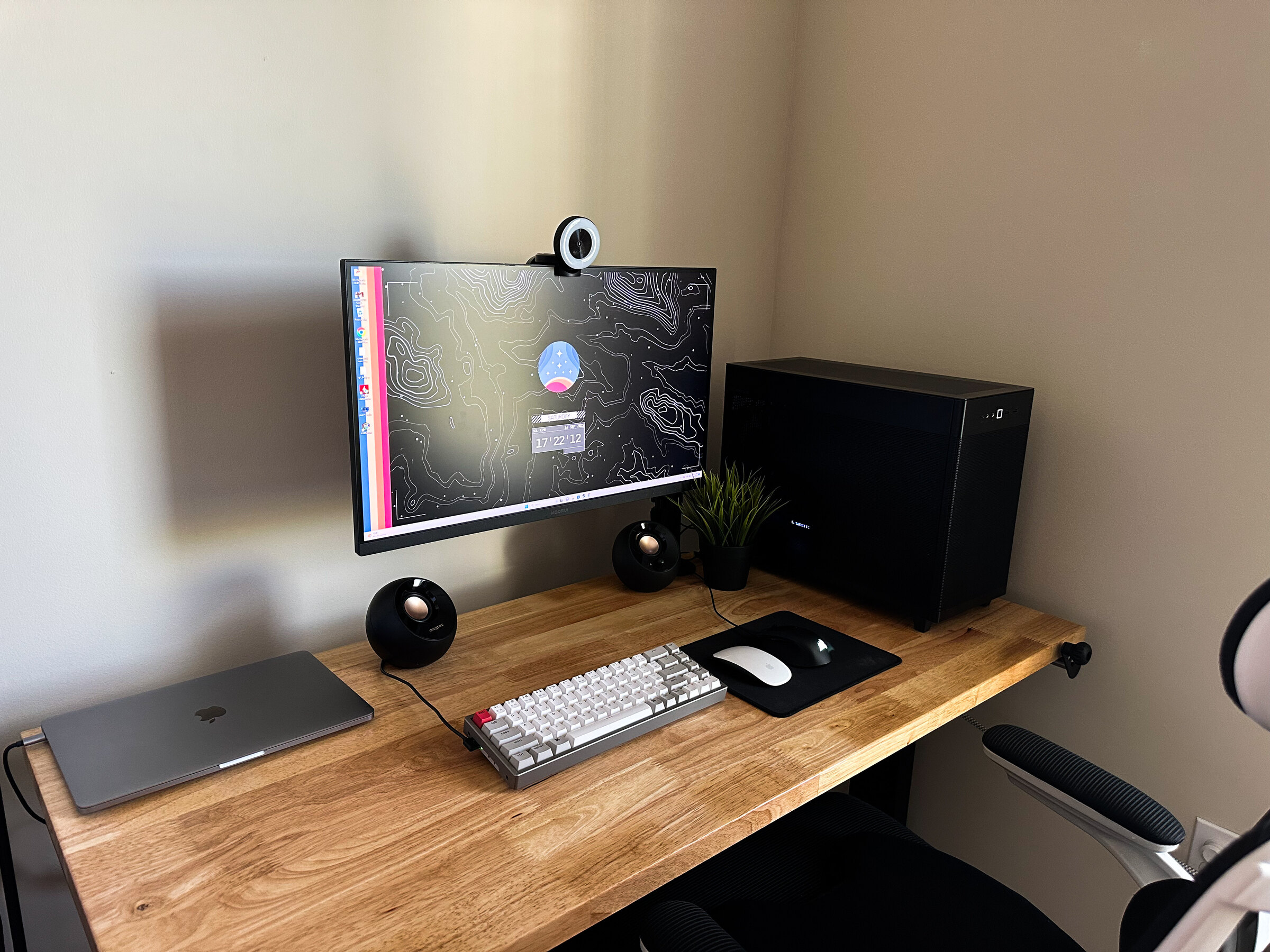 A clean desk setup with a monitor, keyboard, trackpad, and webcam.